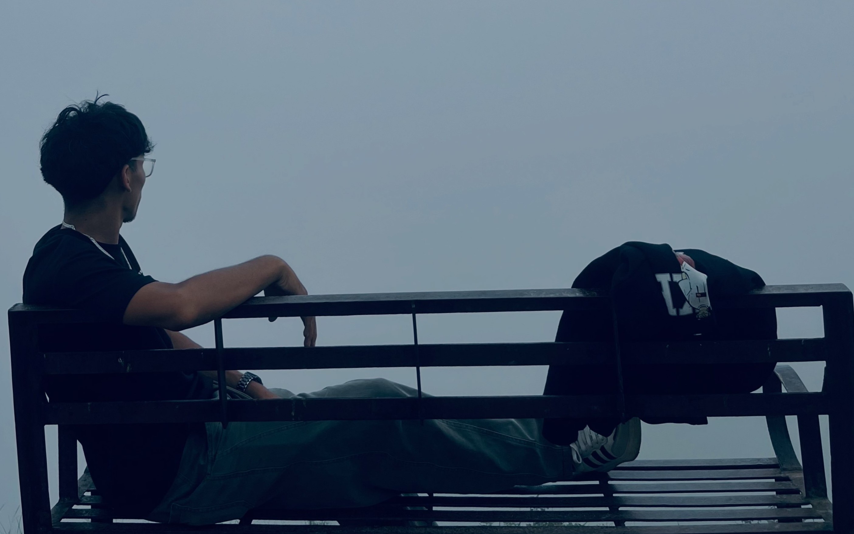 Raja Shahi resting on a viewpoint bench gazing into the sea of morning mist